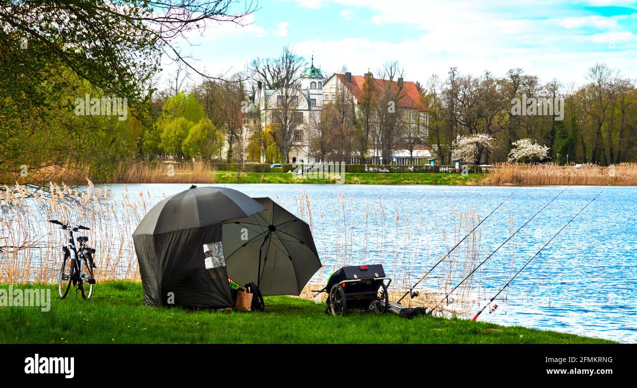 Umbrella tent, fishing rods, bicycle and luggage trailer on the shore of  blue lake fishing Stock Photo - Alamy