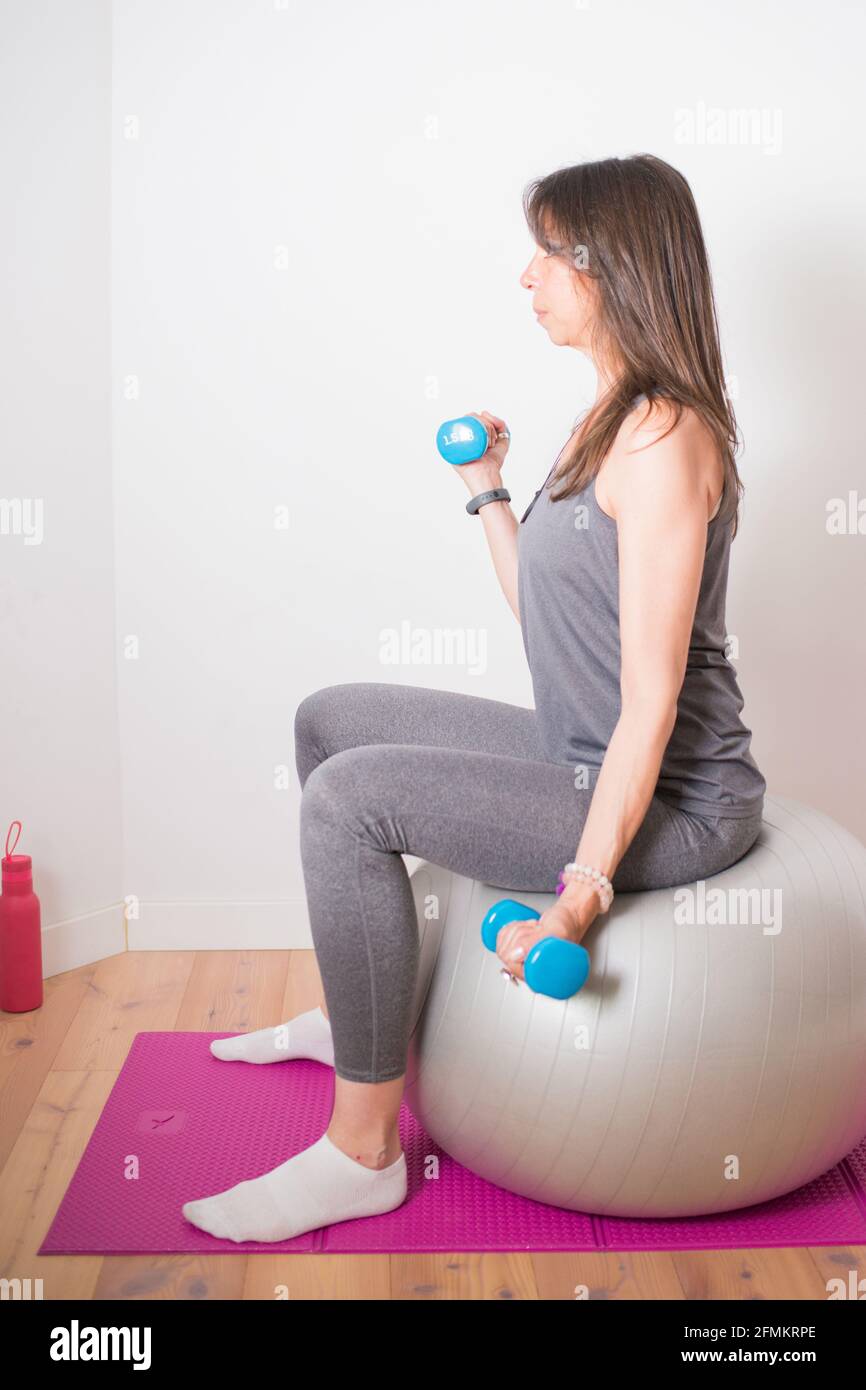 Caucasian attractive woman training at home with dumbbells and ...