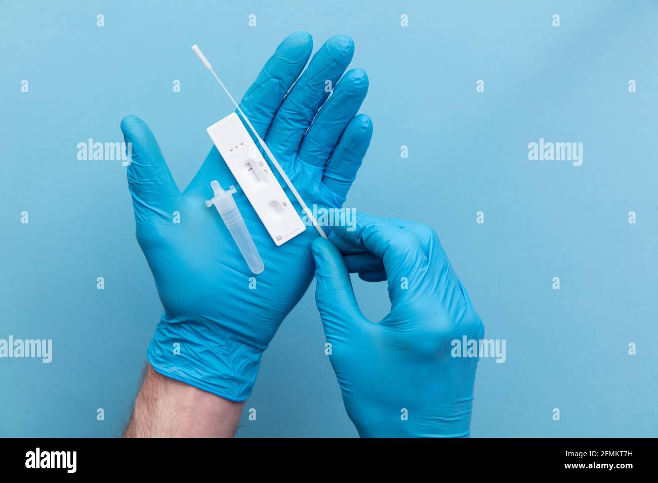 Doctor in blue gloves using a lateral flow covid-19 testing kit Stock Photo