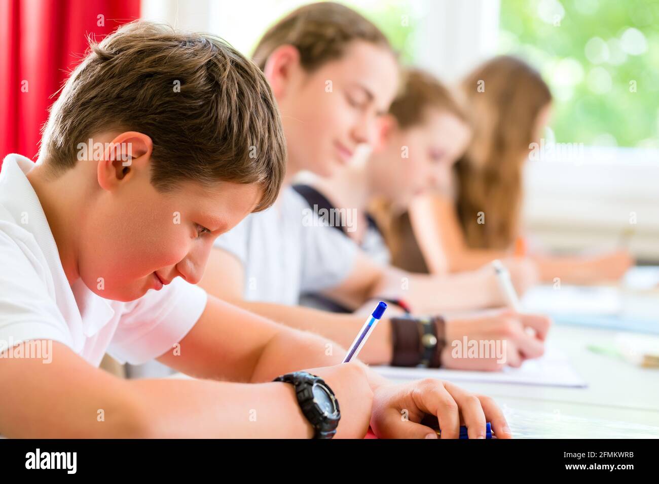 Students or pupils of school class writing an exam test in classroom ...