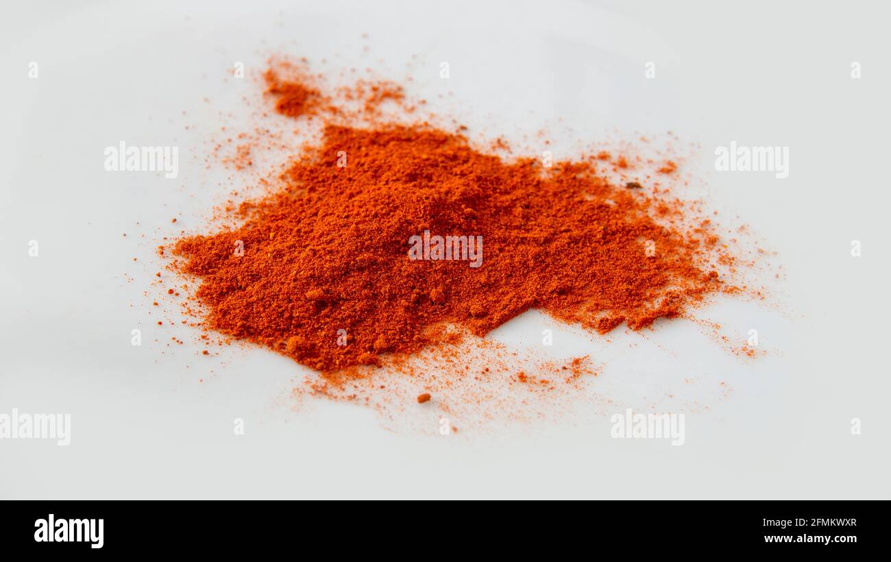 close view of a pile of paprika red powder over a white surface Stock Photo
