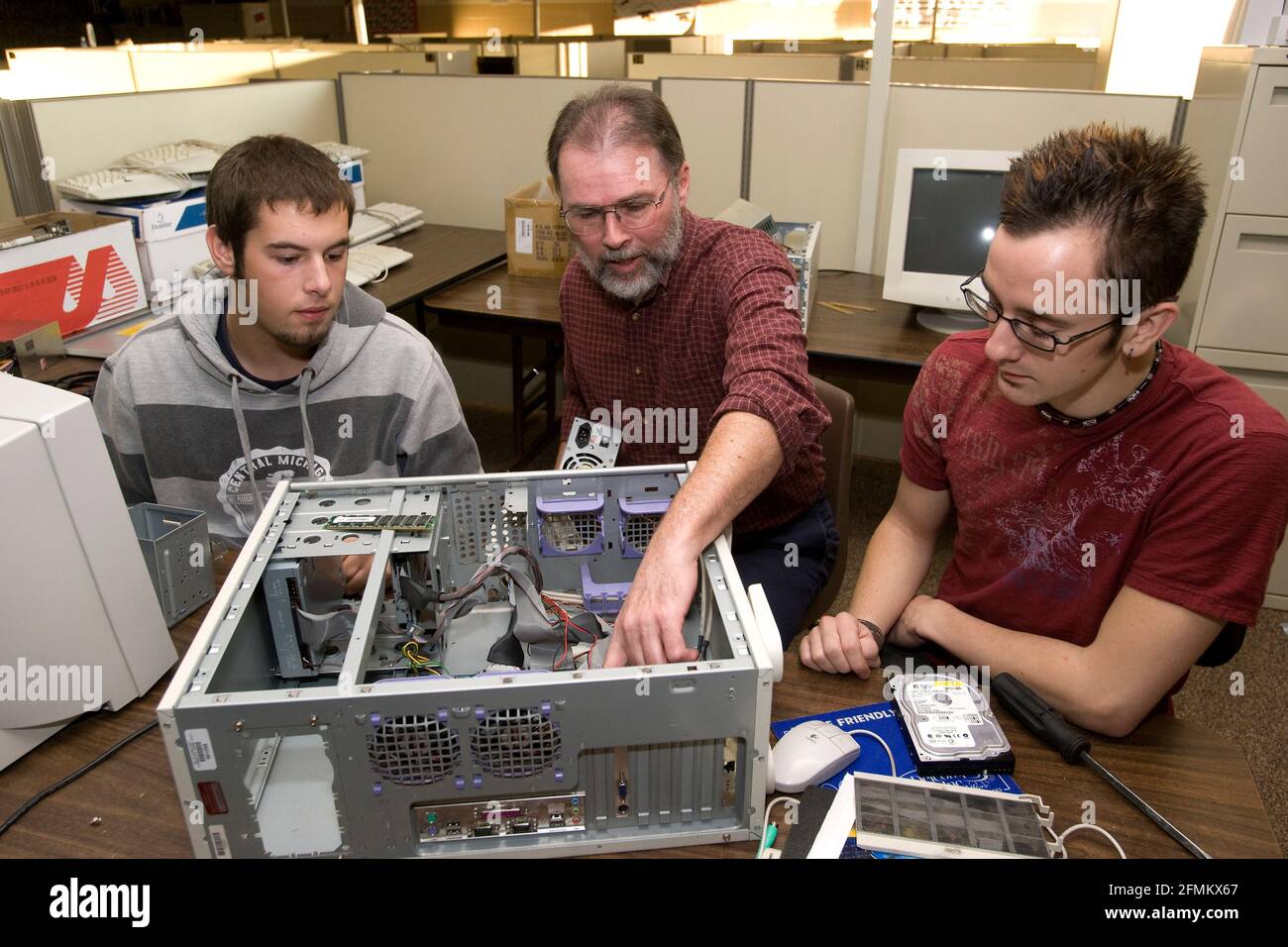 Teacher instructs two high school students in vocational, computer repair class Stock Photo