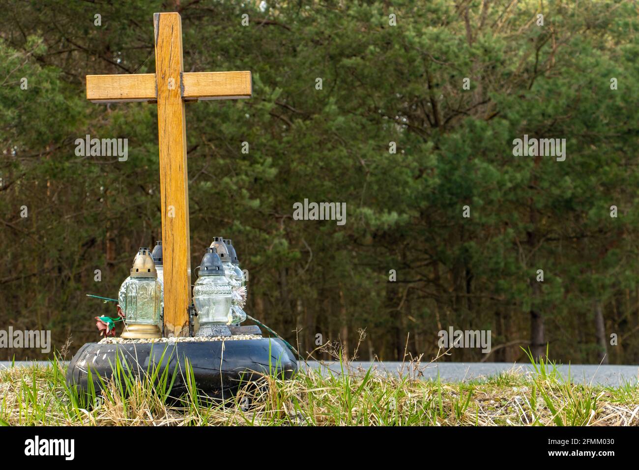 A roadside memorial cross with a candles commemorating the tragic death beside a road. Stock Photo