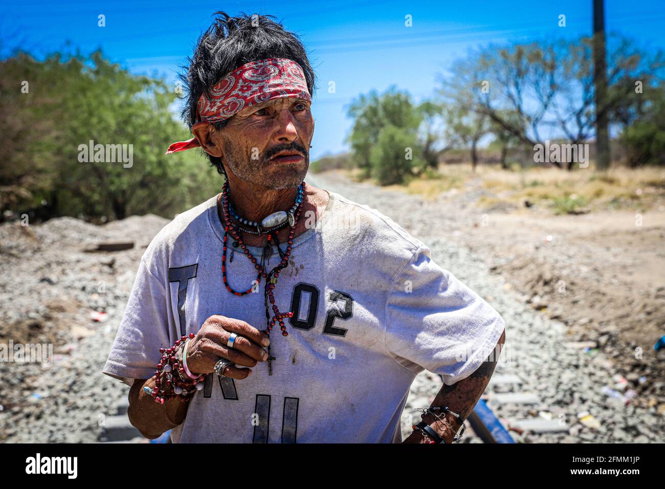 Portrait of a man whose name is unknown in addition to being homeless or  destitute in poverty, he wears a red bandana on his forehead and several  bracelets, necklaces and rings. He