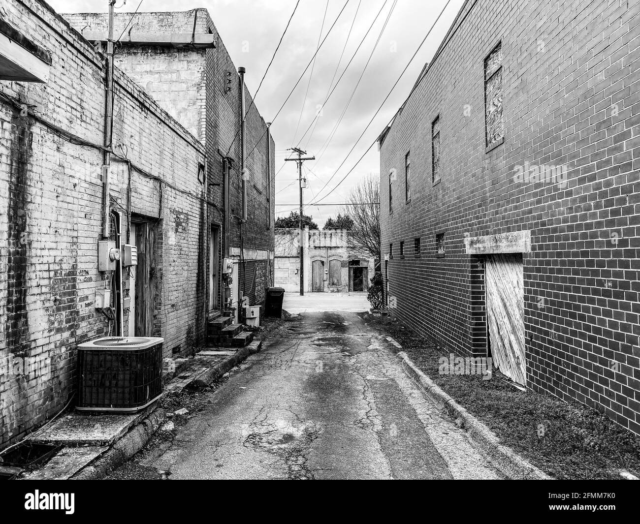 deserted abandoned rural town back alley in dark lonely moody despair black and white as an architecture scene Stock Photo