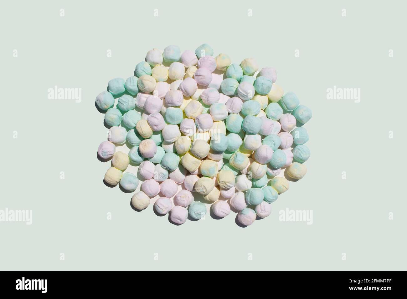 after dinner mints in pink yellow and green colors in a heap pile on a light off white studio space as food scene Stock Photo