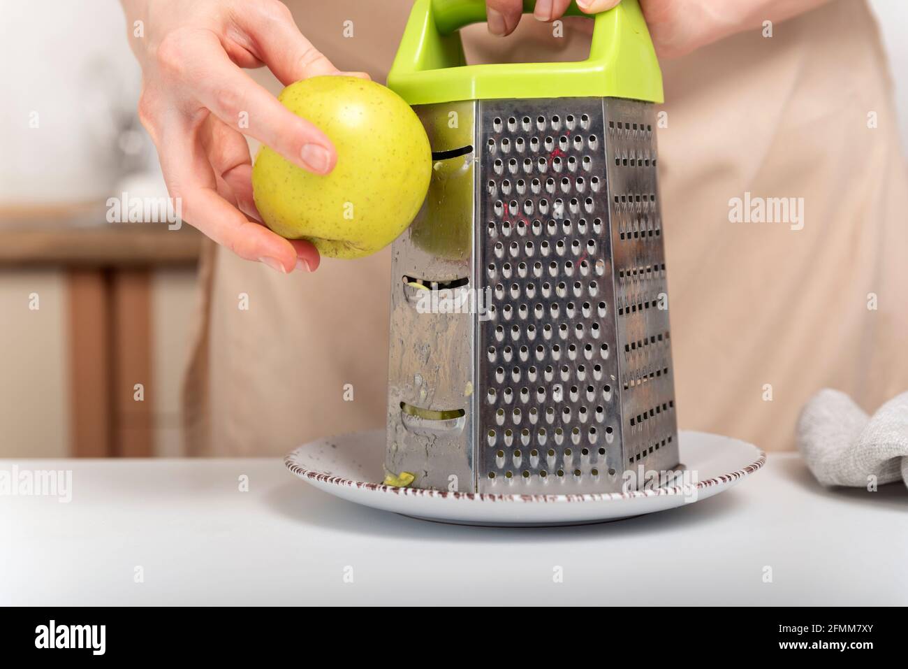 Cook is grating an apple. Preparing baking ingredients. Stock Photo