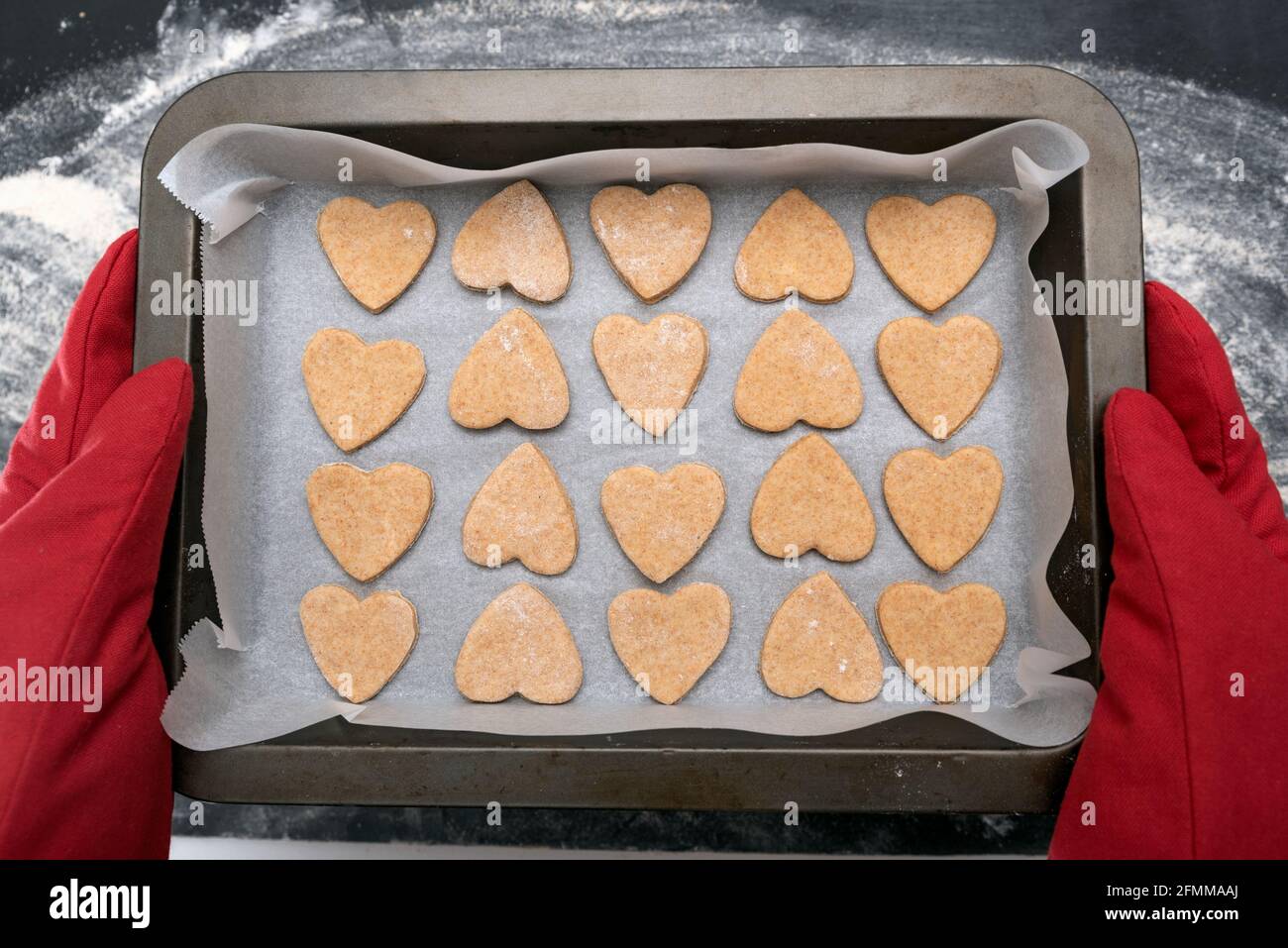 Chief in oven mitts holding freshly baked heart-shaped cookies. Top view  Stock Photo - Alamy