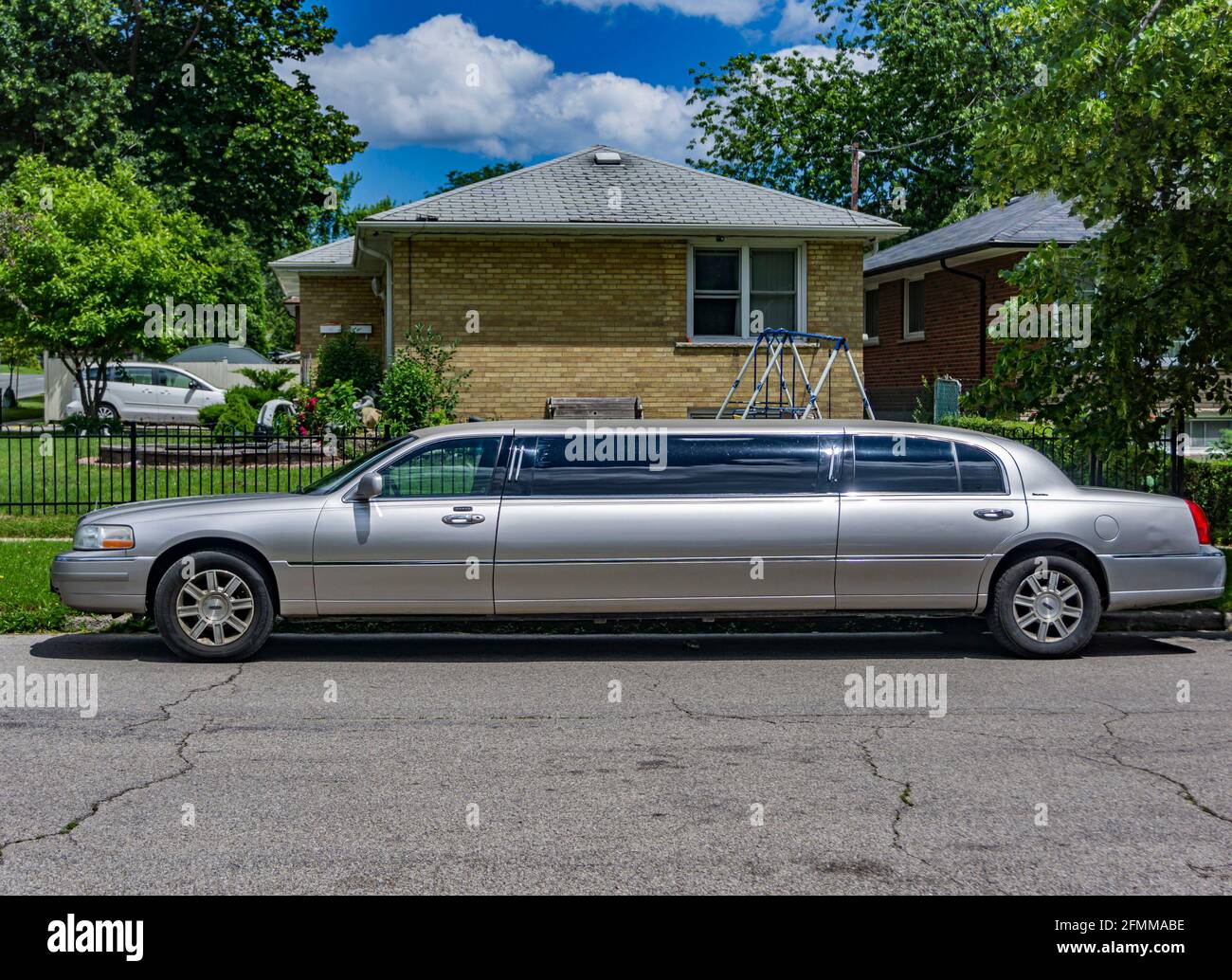 Silver colour stretch limousine parked by the sidewalk of a residential neighbourhood Stock Photo