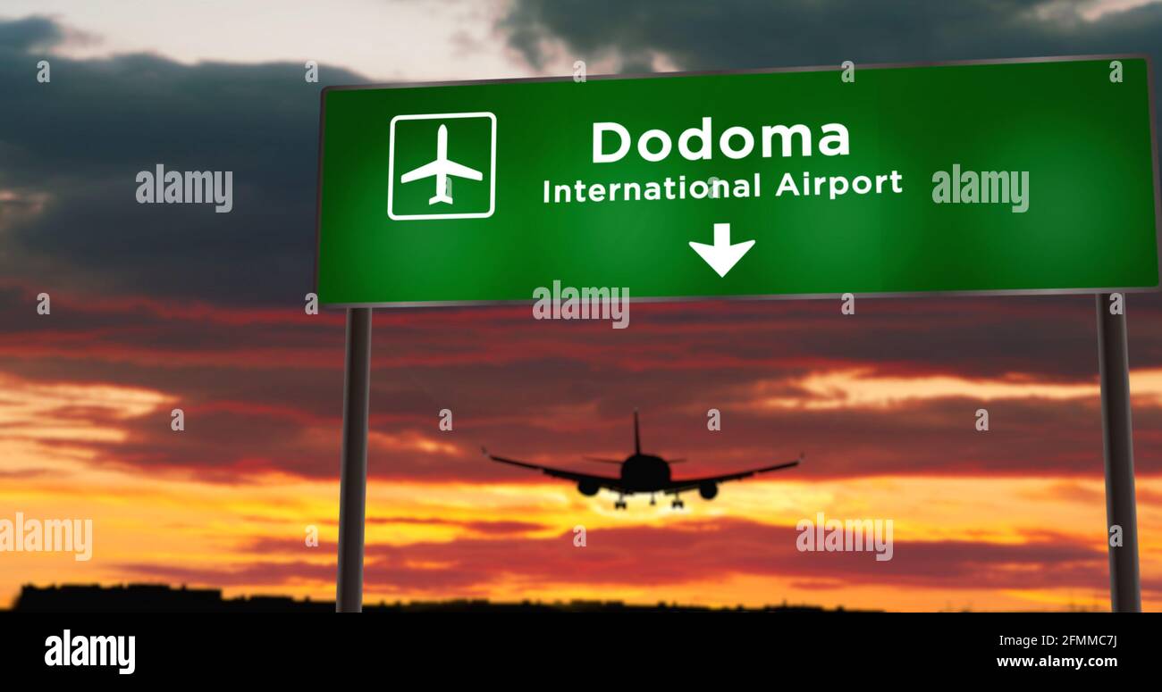 Airplane silhouette landing in Dodoma, Tanzania. City arrival with airport direction signboard and sunset in background. Trip and transportation conce Stock Photo