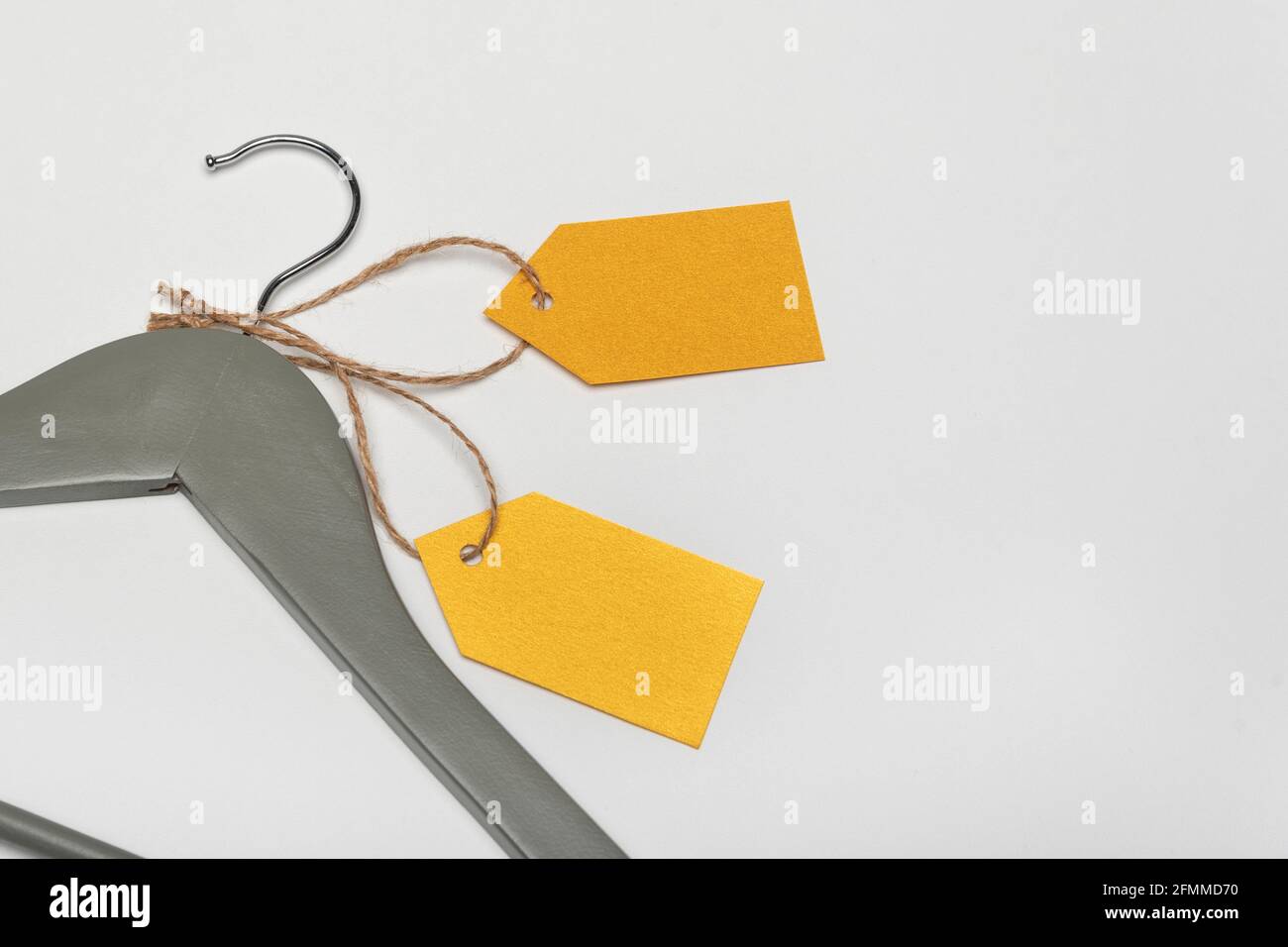 Grey coat hanger with yellow paper labels. White background. Blank label , mockup. Clothing tag