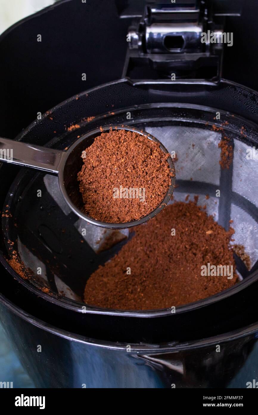 Spoon pours coffee into the container of the coffee maker close up Stock Photo