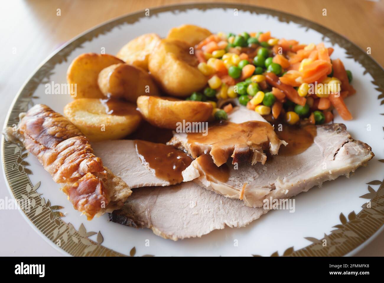 Home cooked pork roast dinner with crackling, gravy, roast potatoes and