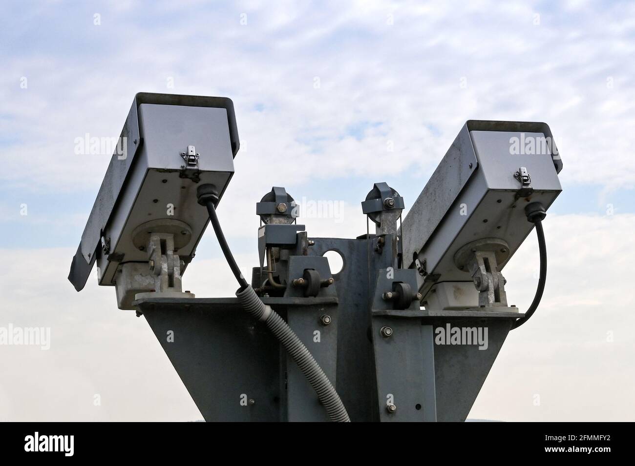 Pair of remote controlled CCTV video cameras isolated against a clear sky. No people. Stock Photo