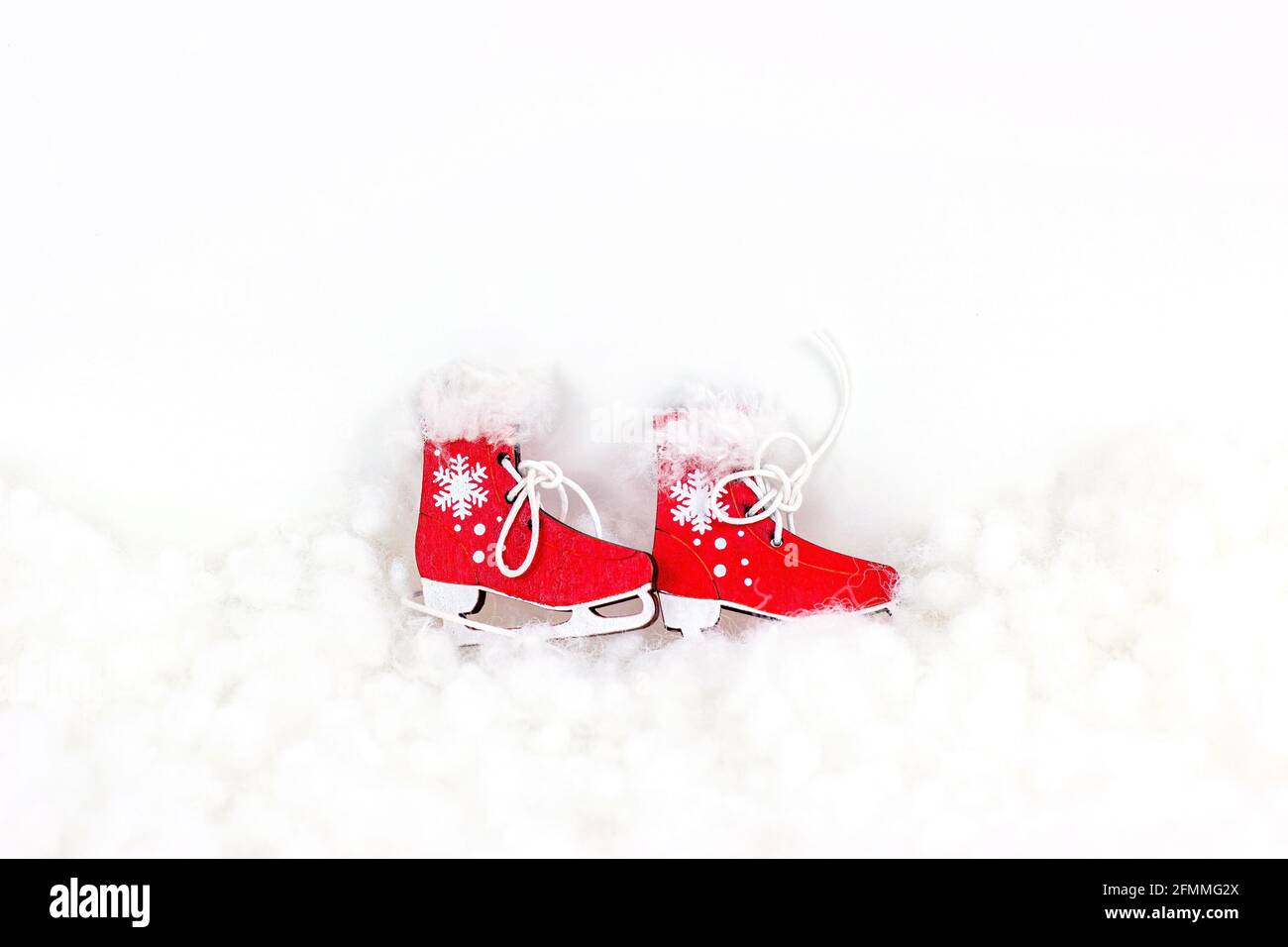 Bright red vintage toy skating shoes on white artificial snow background with copy space. Winter sports, Christmas and New Year holiday design concept Stock Photo