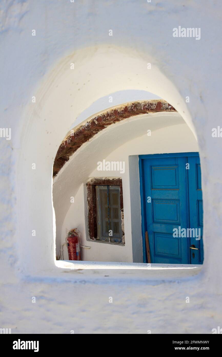 Blue door of traditional whitewashed home framed by window, Oia, Santorini, Greece Stock Photo
