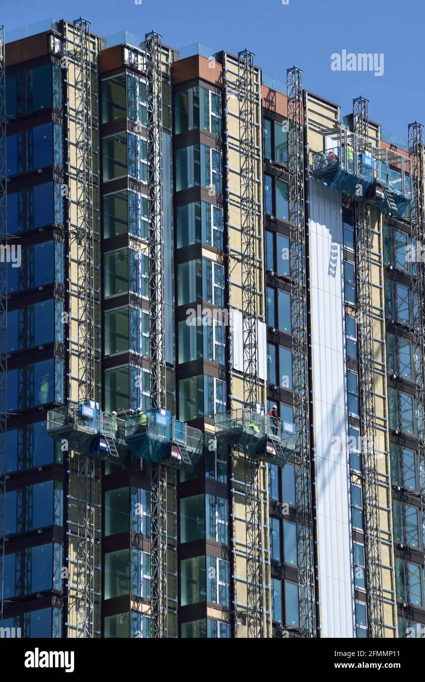 Construction workers in cradles building a highrise apartment block in