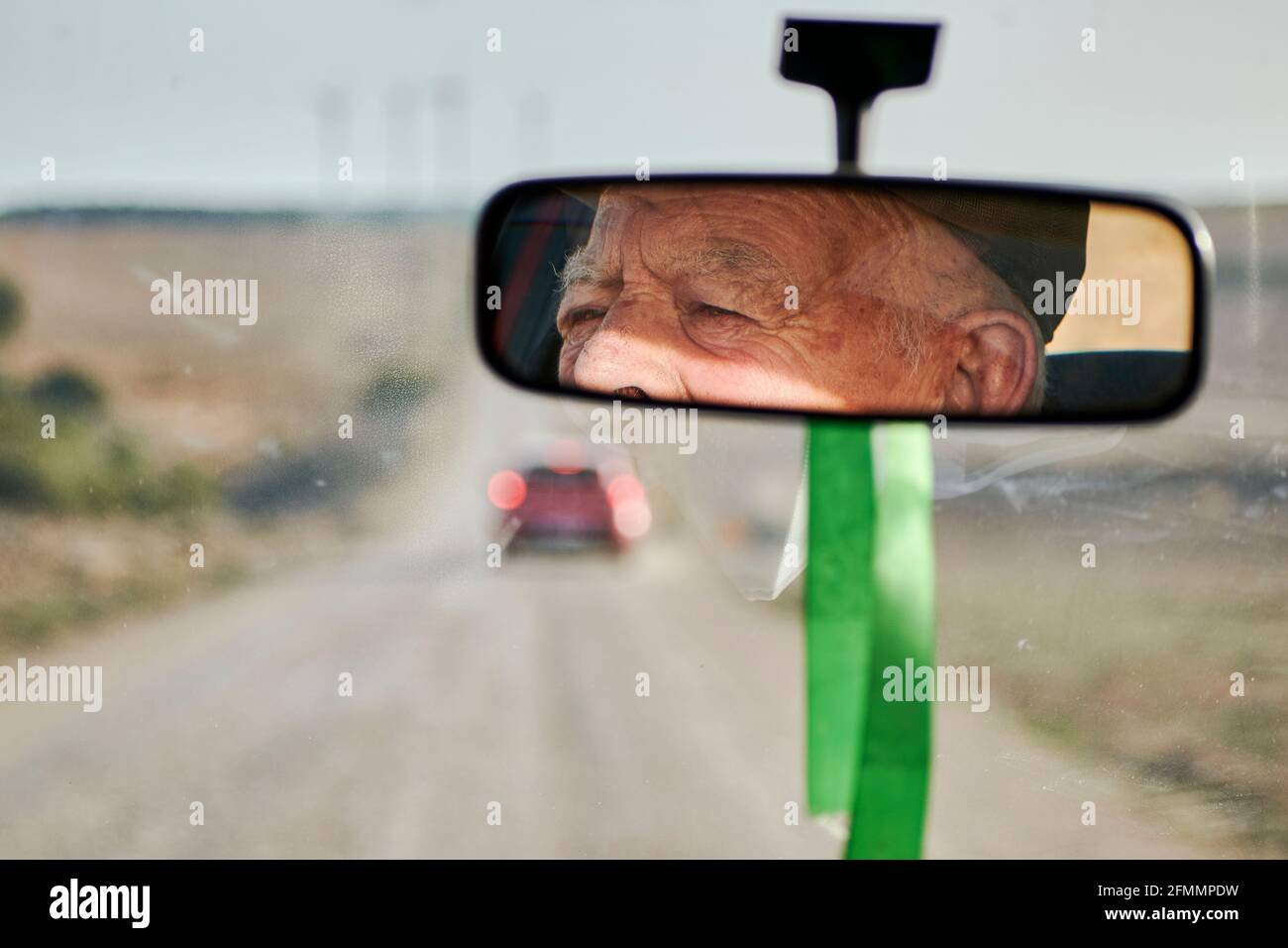 View from the rearview mirror of a car of an elderly man driving Stock Photo