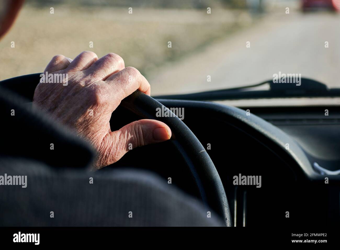 Hands of an elderly man holding the steering wheel of a vehicle Stock Photo