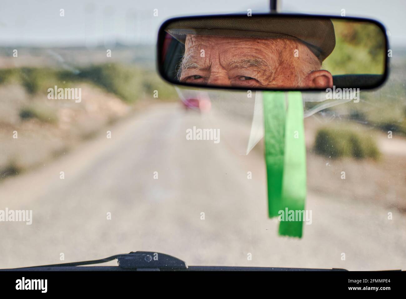 View from the rearview mirror of a car of an elderly man driving Stock Photo