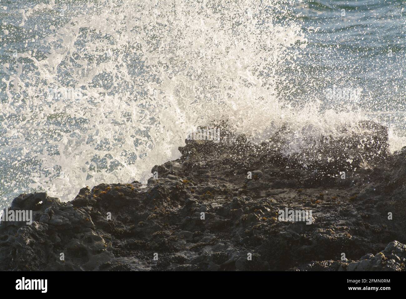 waves crashing on jagged black rocks Stock Photo