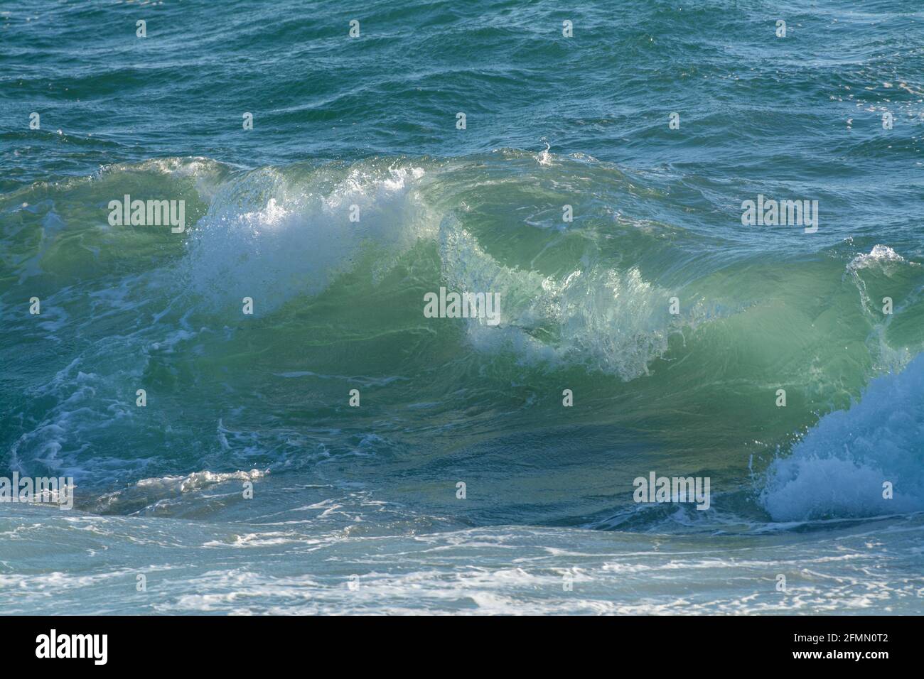 waves crashing on jagged black rocks Stock Photo