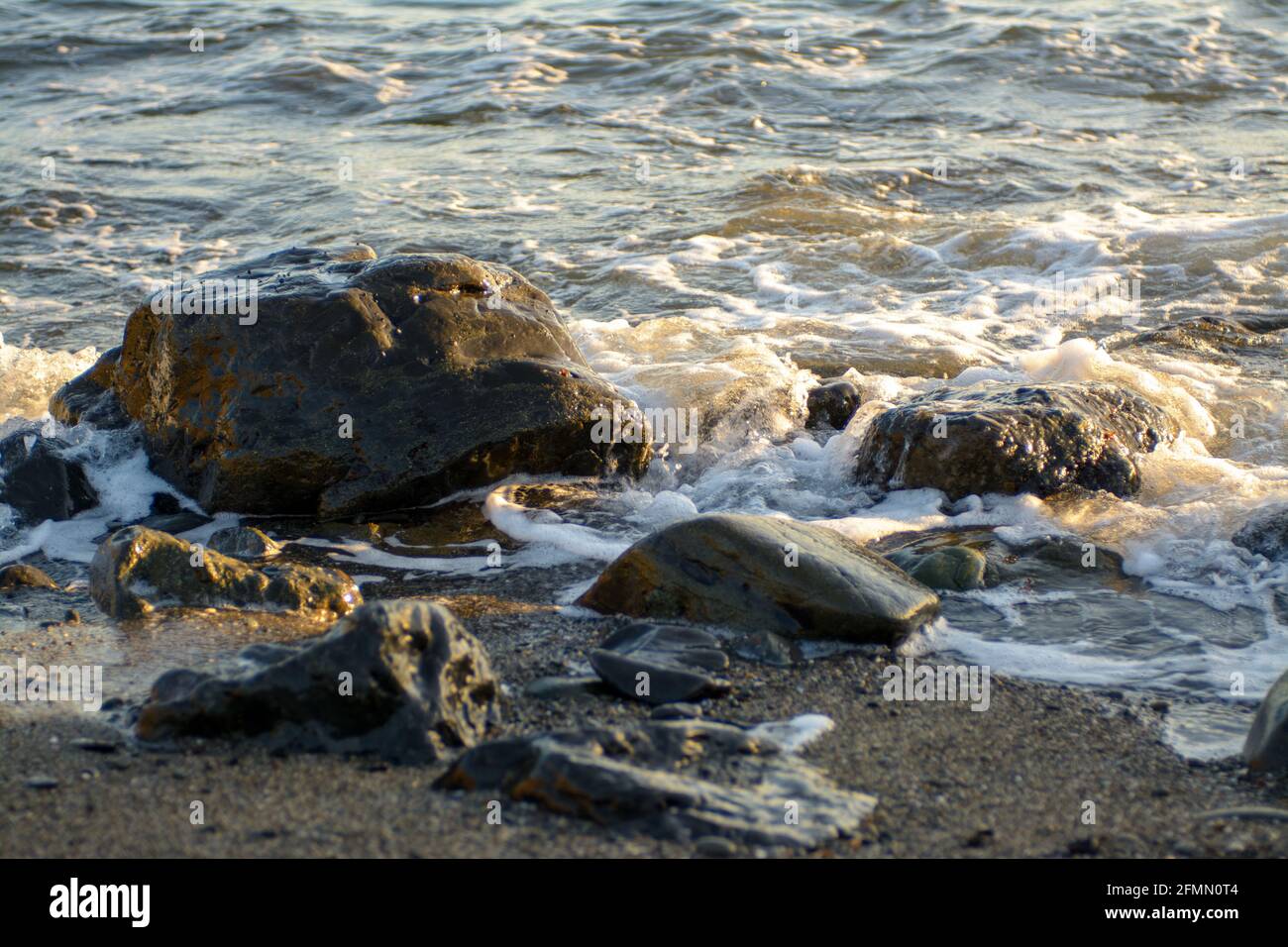 waves crashing on jagged black rocks Stock Photo