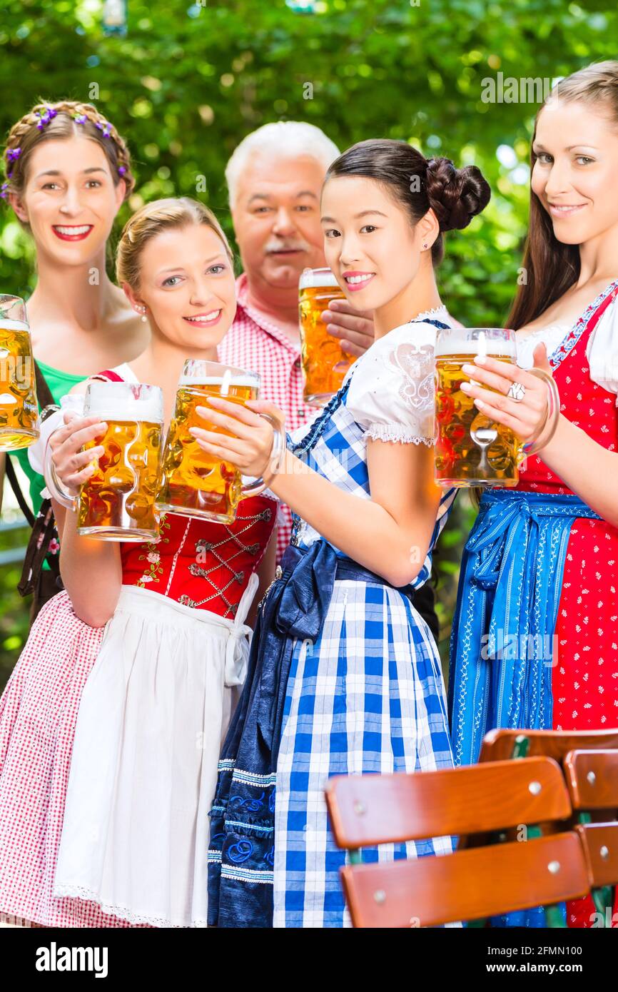 In Beer garden - friends, man and women in Tracht, Dirndl and Lederhosen  drinking a fresh beer in Bavaria, Germany Stock Photo - Alamy