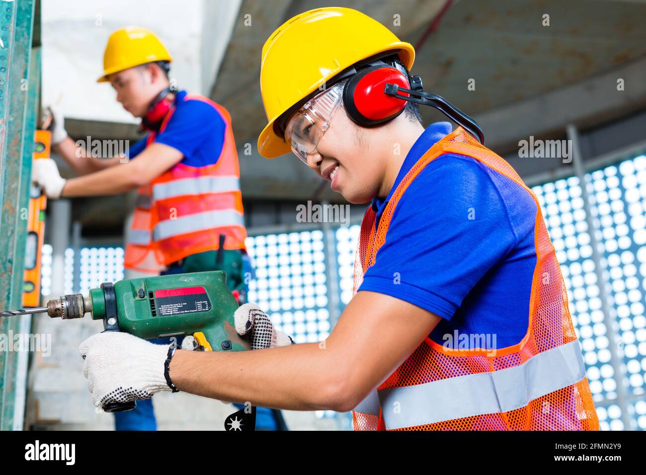 Asian Indonesian construction site workers drilling with a machine or