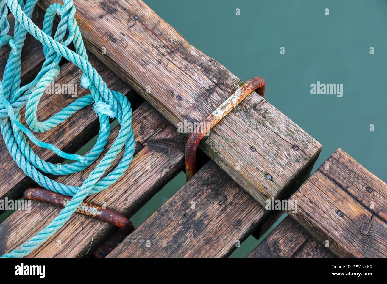 Wooden pier with blue sea. Wood floor or terrace beside the blue crystal clear water and a rope. Stock Photo