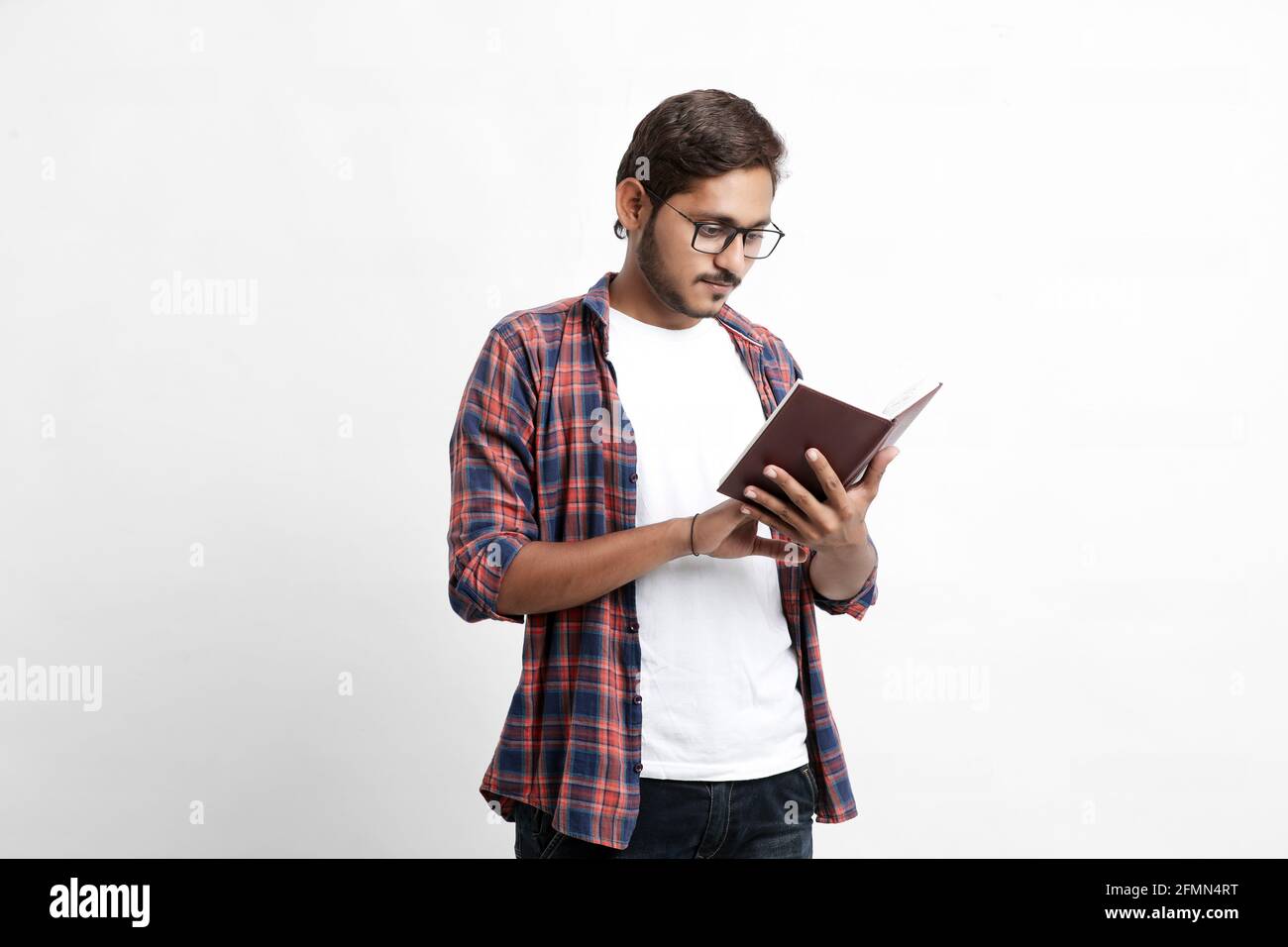 Indian college student reading book on white background. Stock Photo