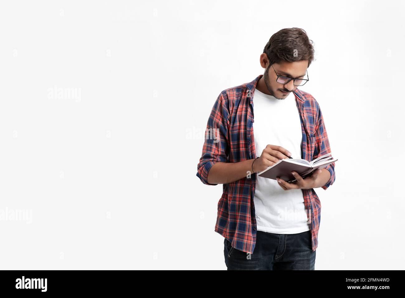 Indian college student reading book on white background. Stock Photo