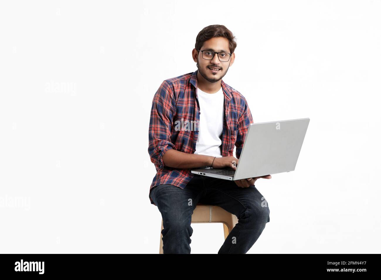 Indian college student using laptop on white background. Stock Photo