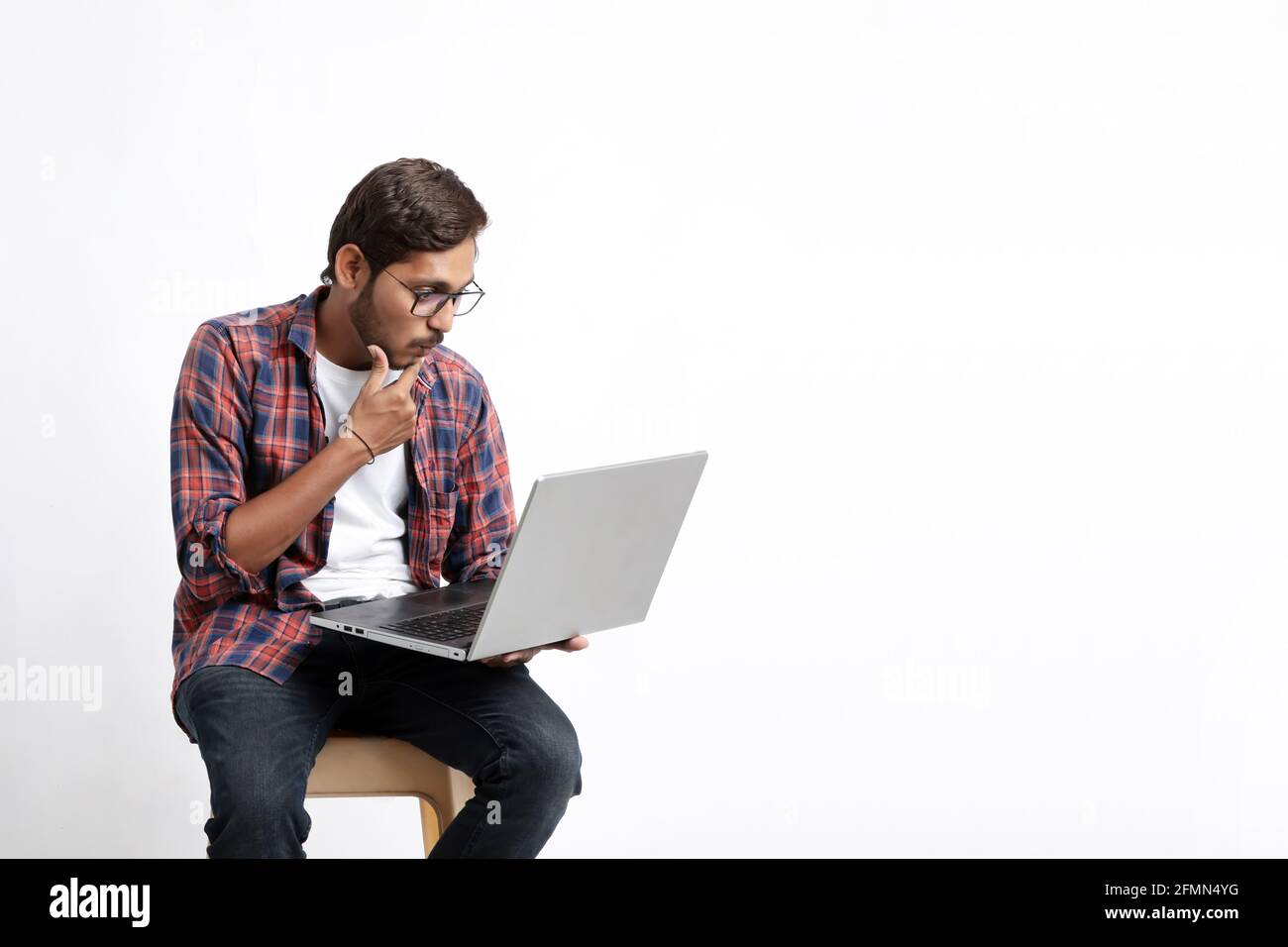 Young indian man using laptop and giving surprised expression. Stock Photo