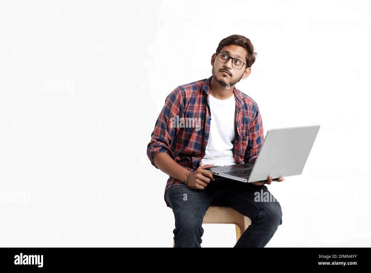 Young indian man thinking some idea when working on laptop. Stock Photo