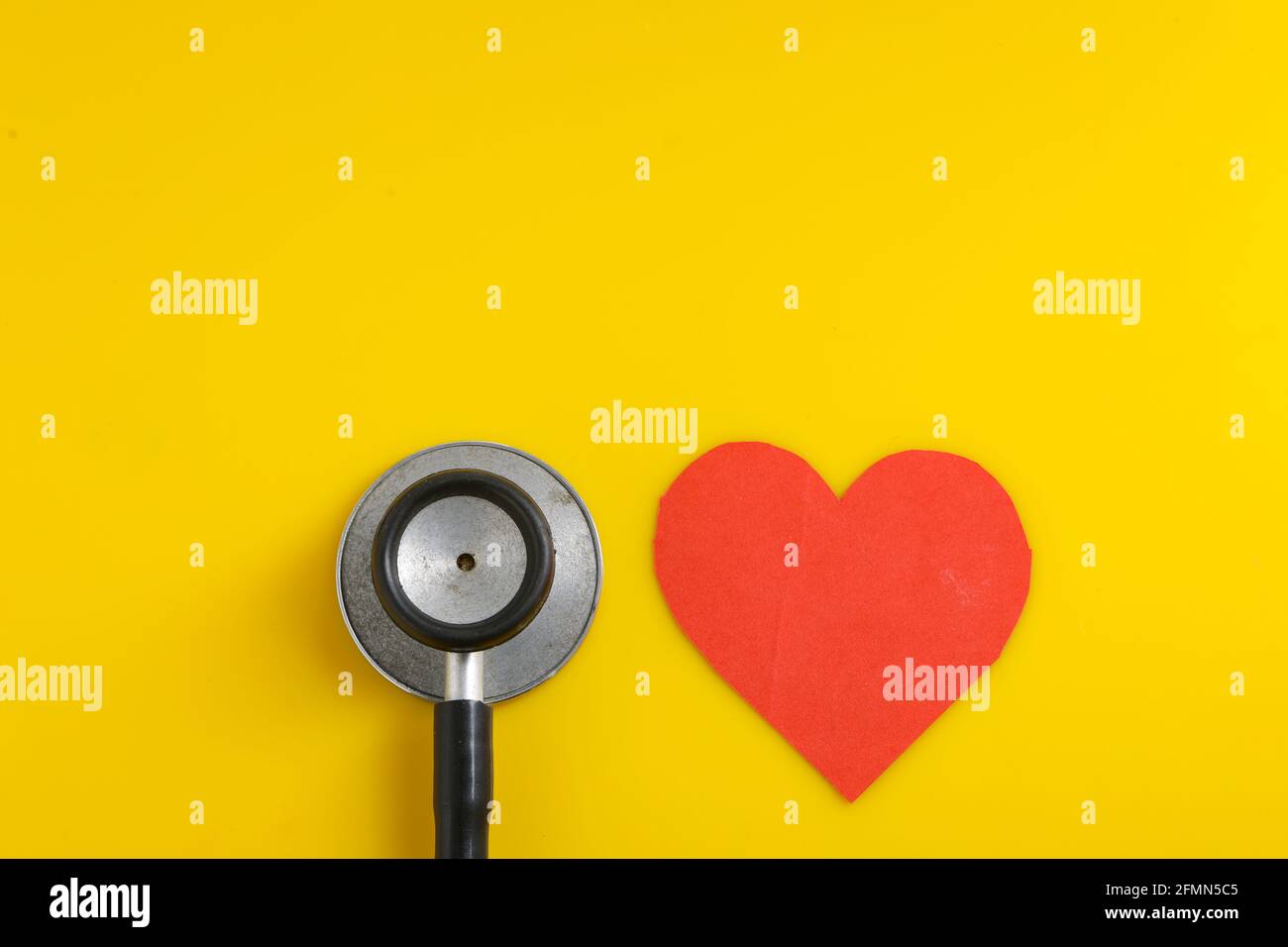 A heart with a stethoscope on yellow background Stock Photo - Alamy