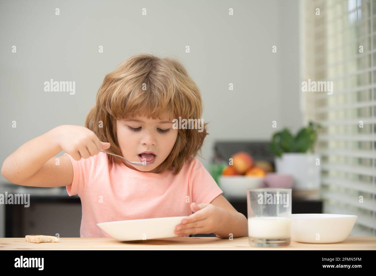 Child eating healthy food at home. Baby eat soup with spoon. Stock Photo