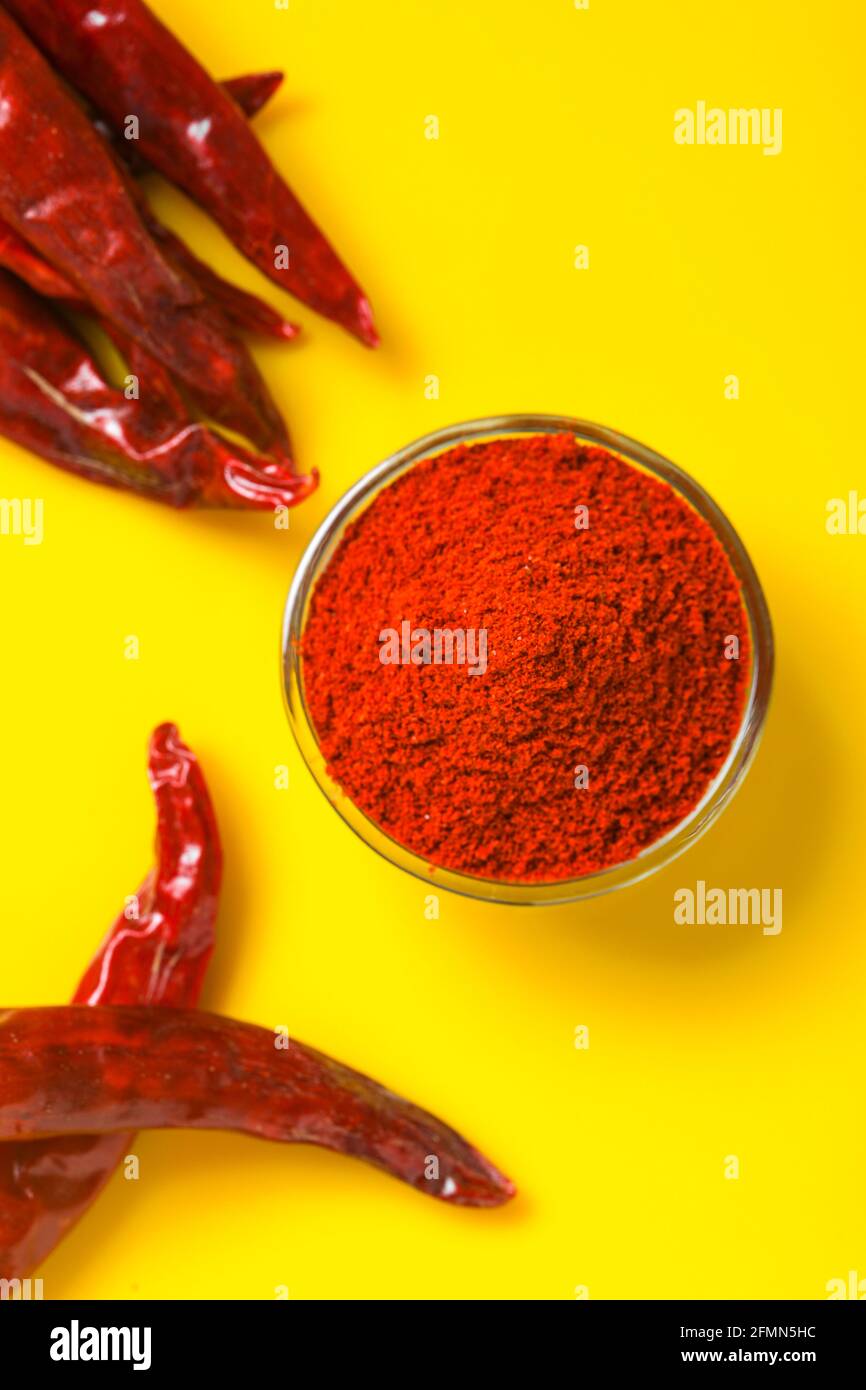 Dry Red chilli with chilli powder in glass bowl on yellow background. Stock Photo