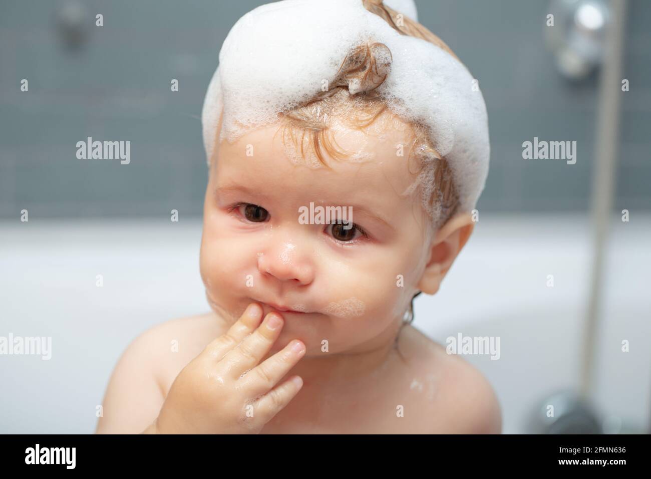 Kid bathing in bathtub. Funny kids face close up. Baby showering
