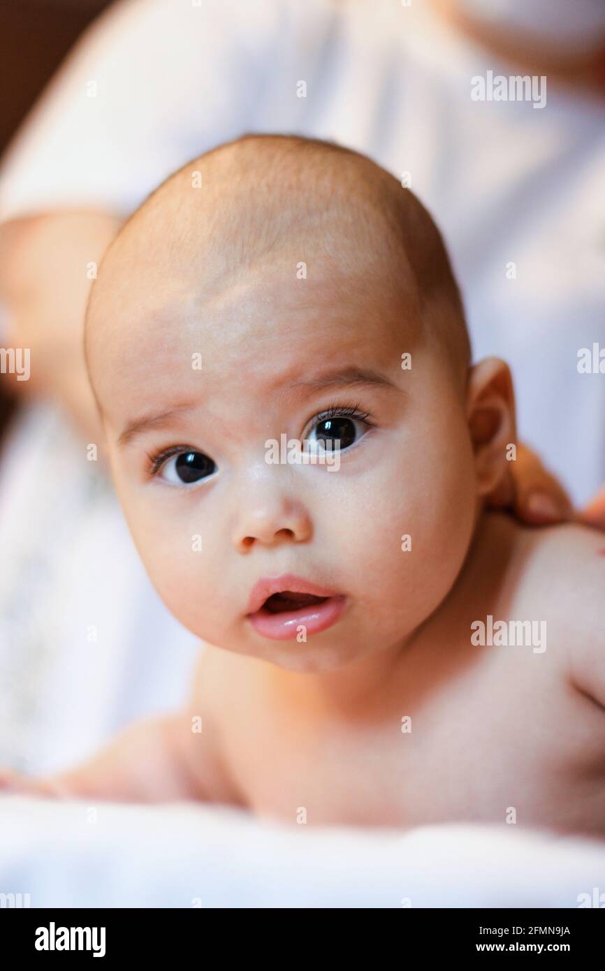 Nurse gives firming massage to sweet baby. Cute infant lying on tummy Stock Photo