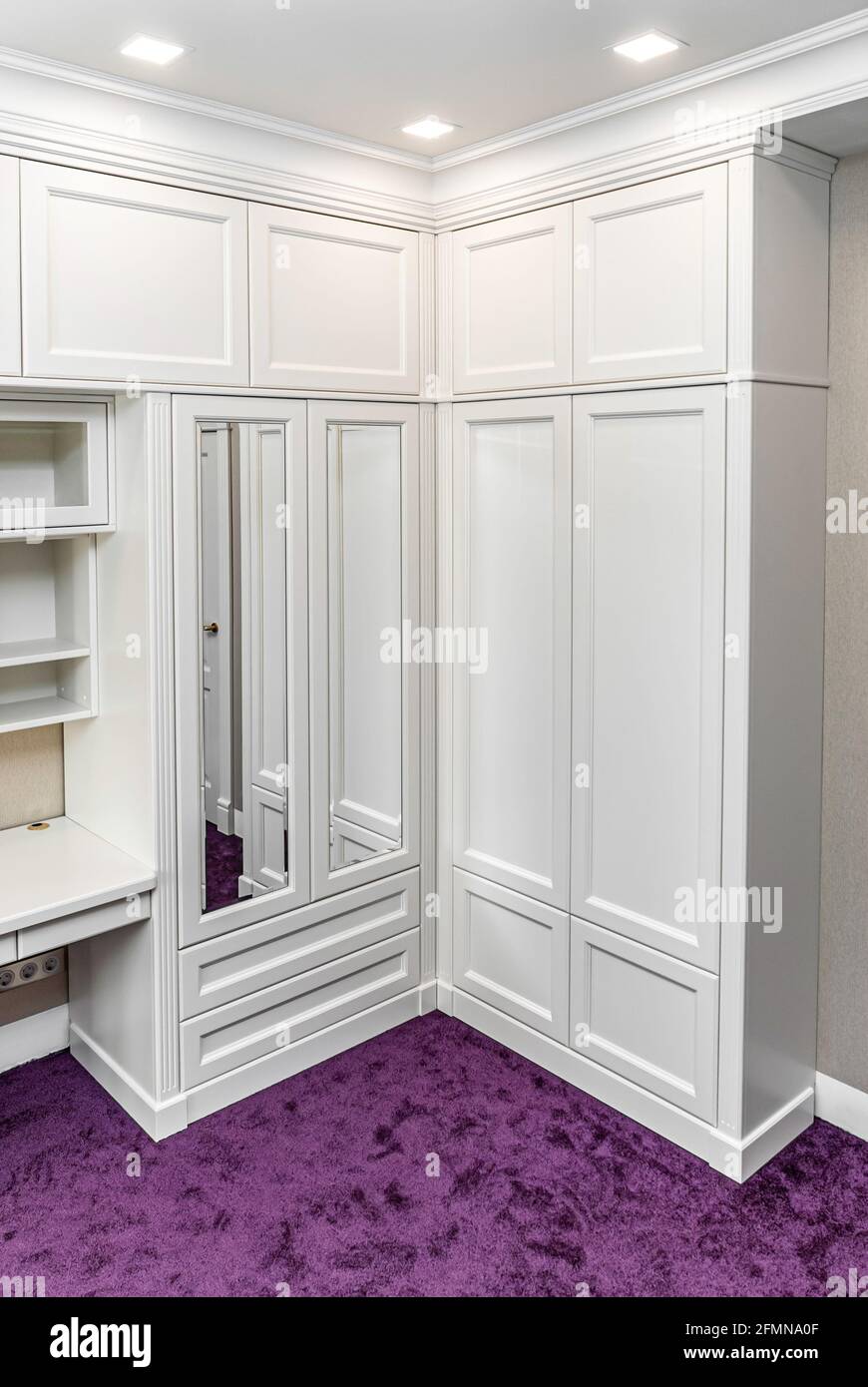 Classical style corner wardrobe with mirrors on a bright purple carpet in a  bright room Stock Photo - Alamy