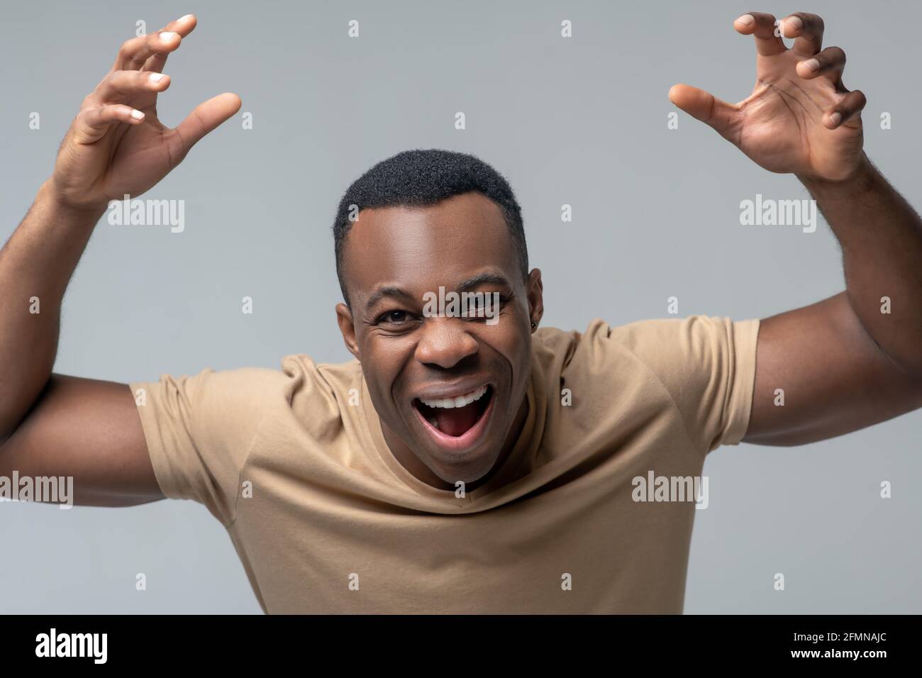 Cheerful man with open mouth and raised hands Stock Photo