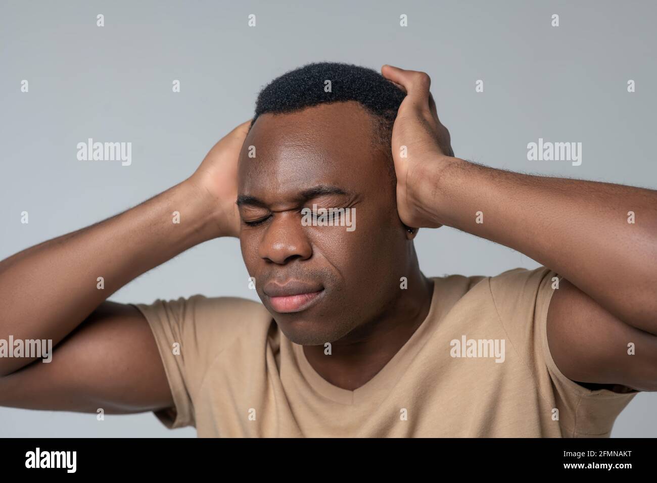 Close-up photo of man covering ears with hands Stock Photo