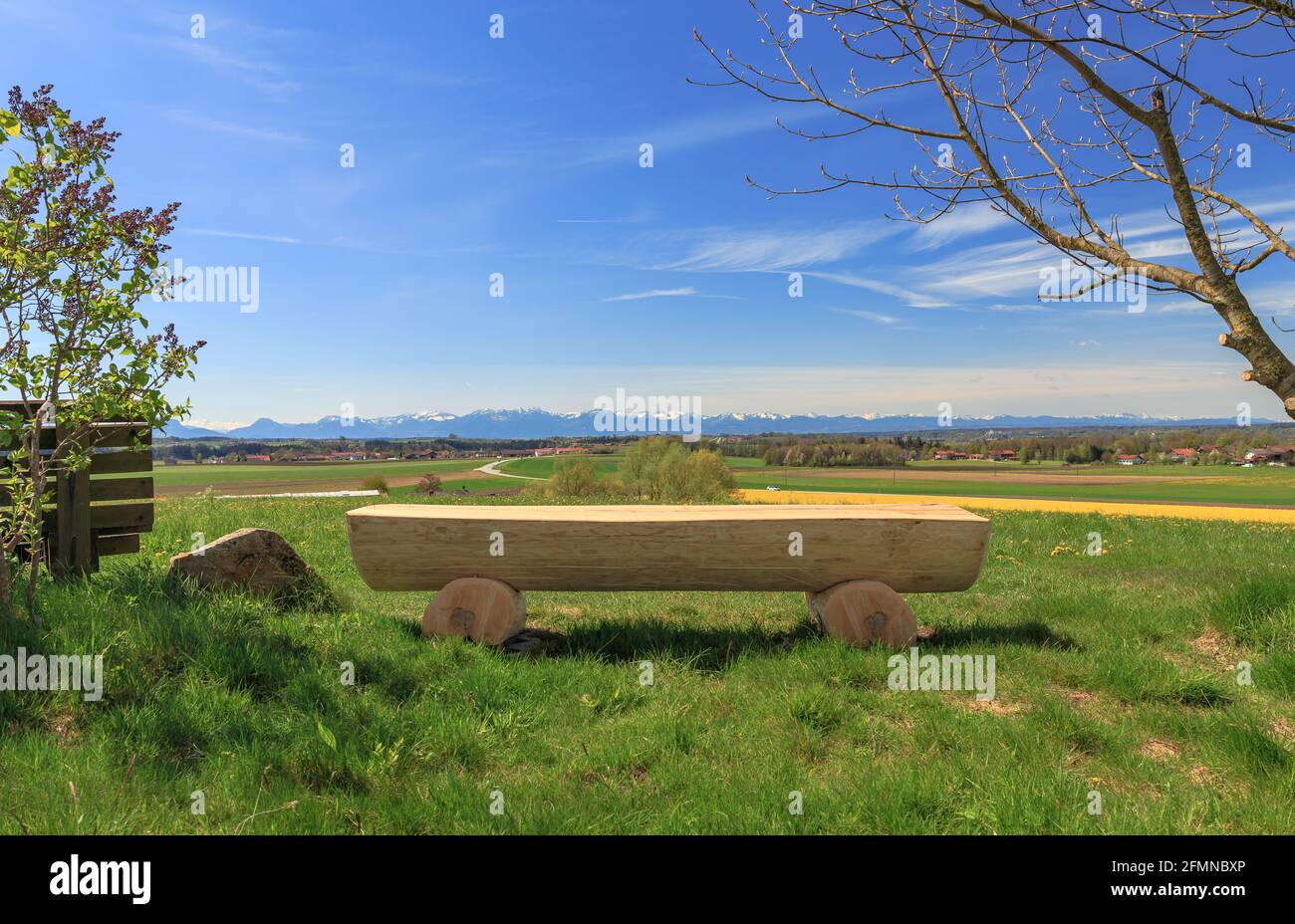 Wooden bench on a viewpoint in the Chiemgau area with view to the alps Stock Photo