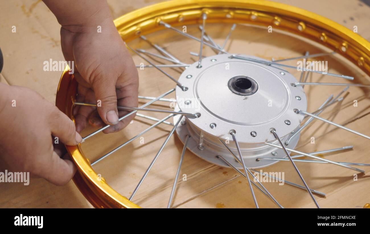 Technician man working motorcycle wheel has spokes weave up on mechanic