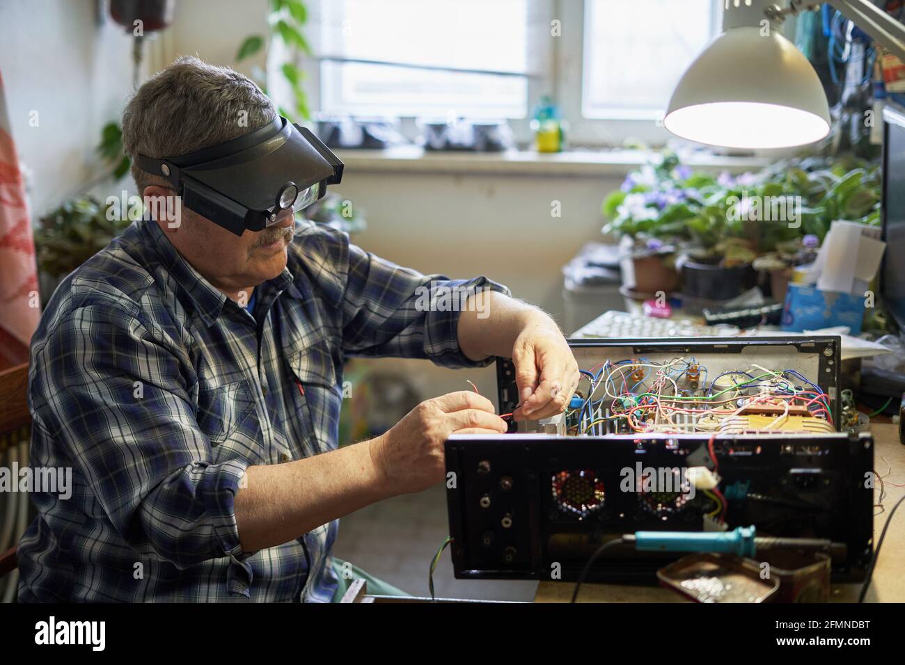 Man with magnifying glasses creates a homemade amplifier Stock Photo