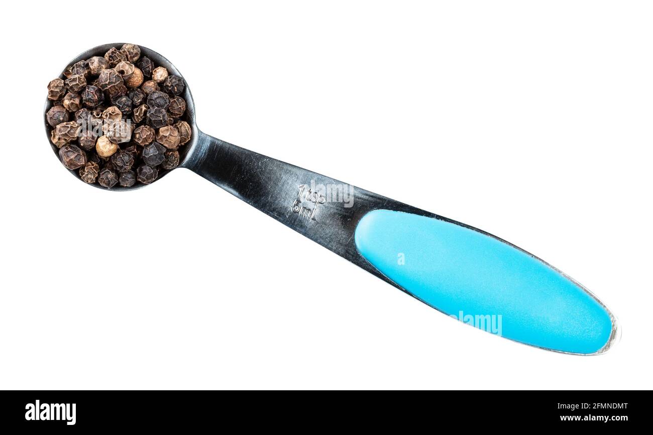 top view of black pepper peppercorns (cooked and dried unripe piper nigrum fruits) in measuring teaspoon cutout on white background Stock Photo