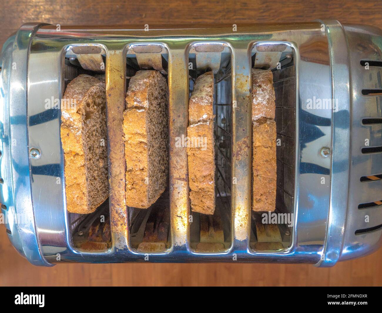Closeup POV overhead shot of four slices of fresh brown bread in the four slots of a retro steel toaster, ready for toasting. Stock Photo