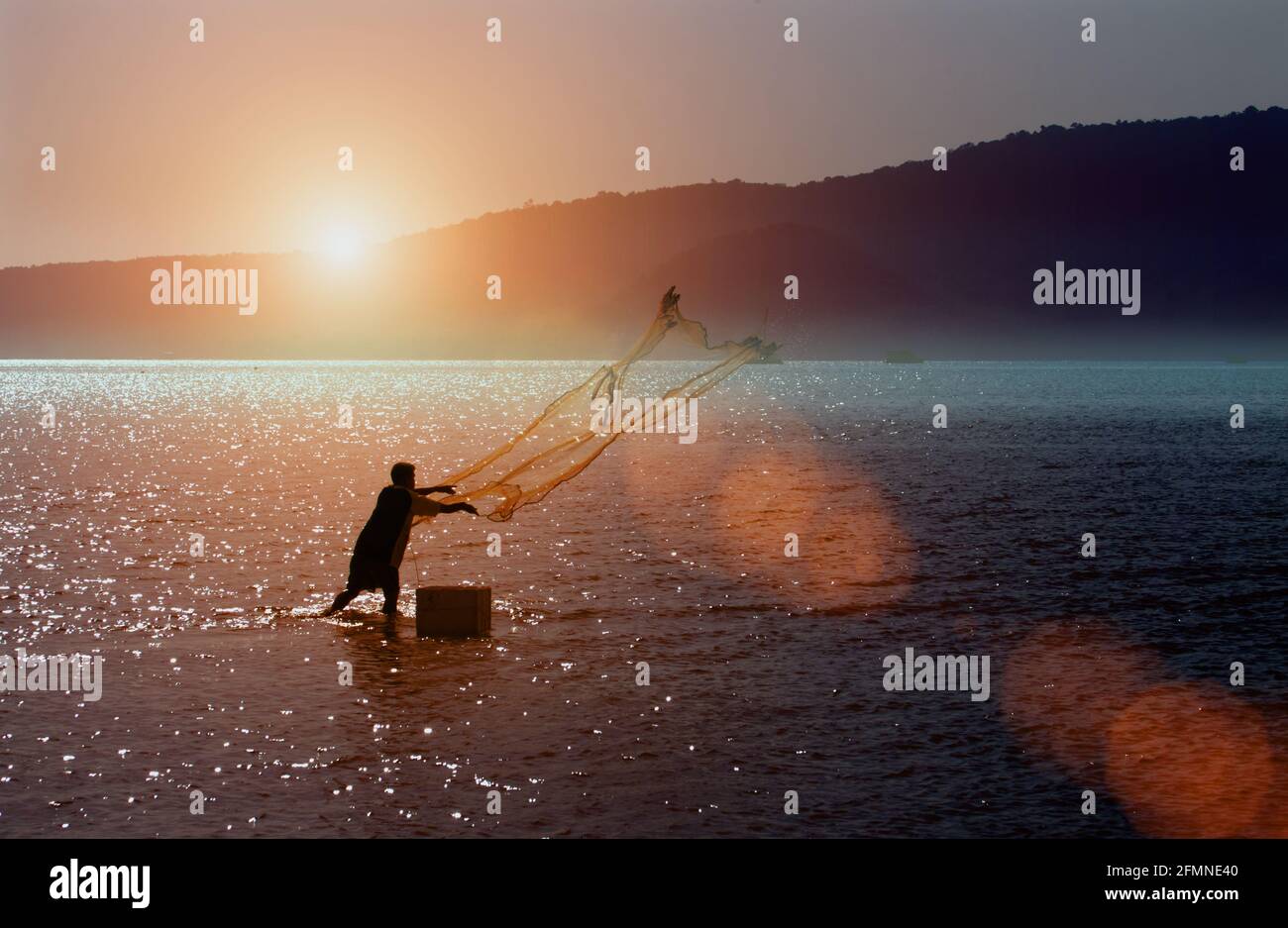 Thai fisherman using a net at sunrise, Phuket, Thailand Stock Photo