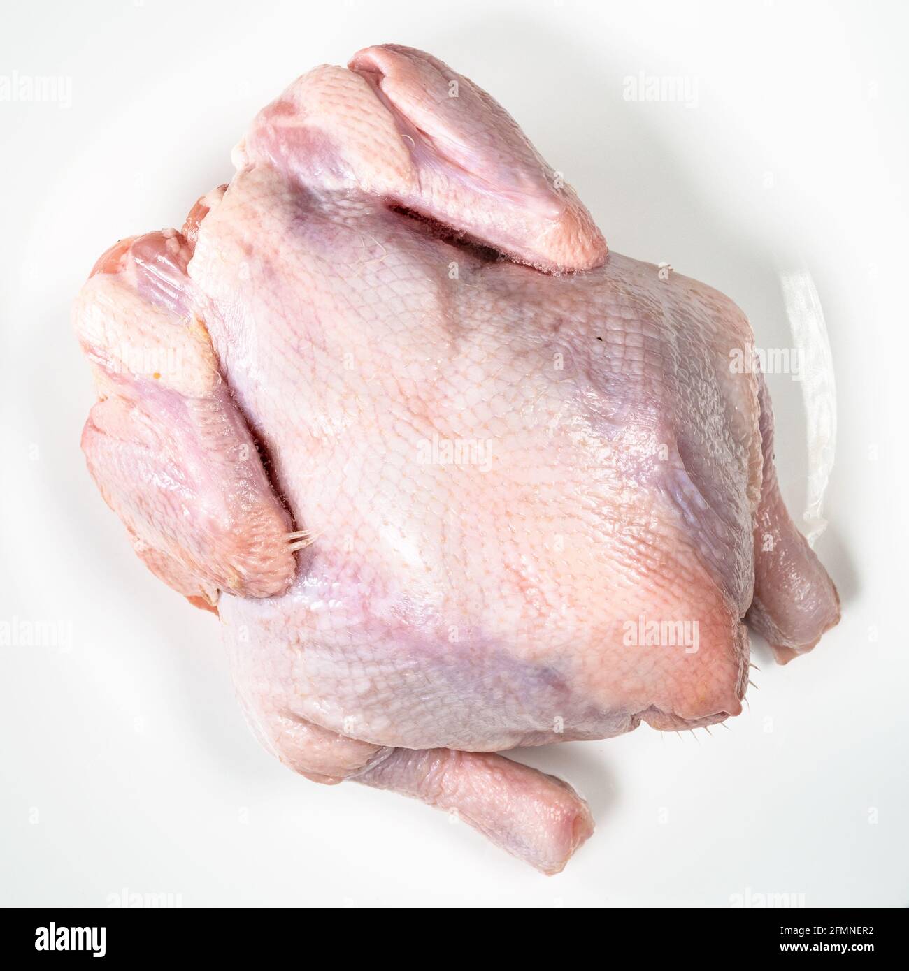 top view of whole air chilled uncooked chicken on white plate Stock Photo